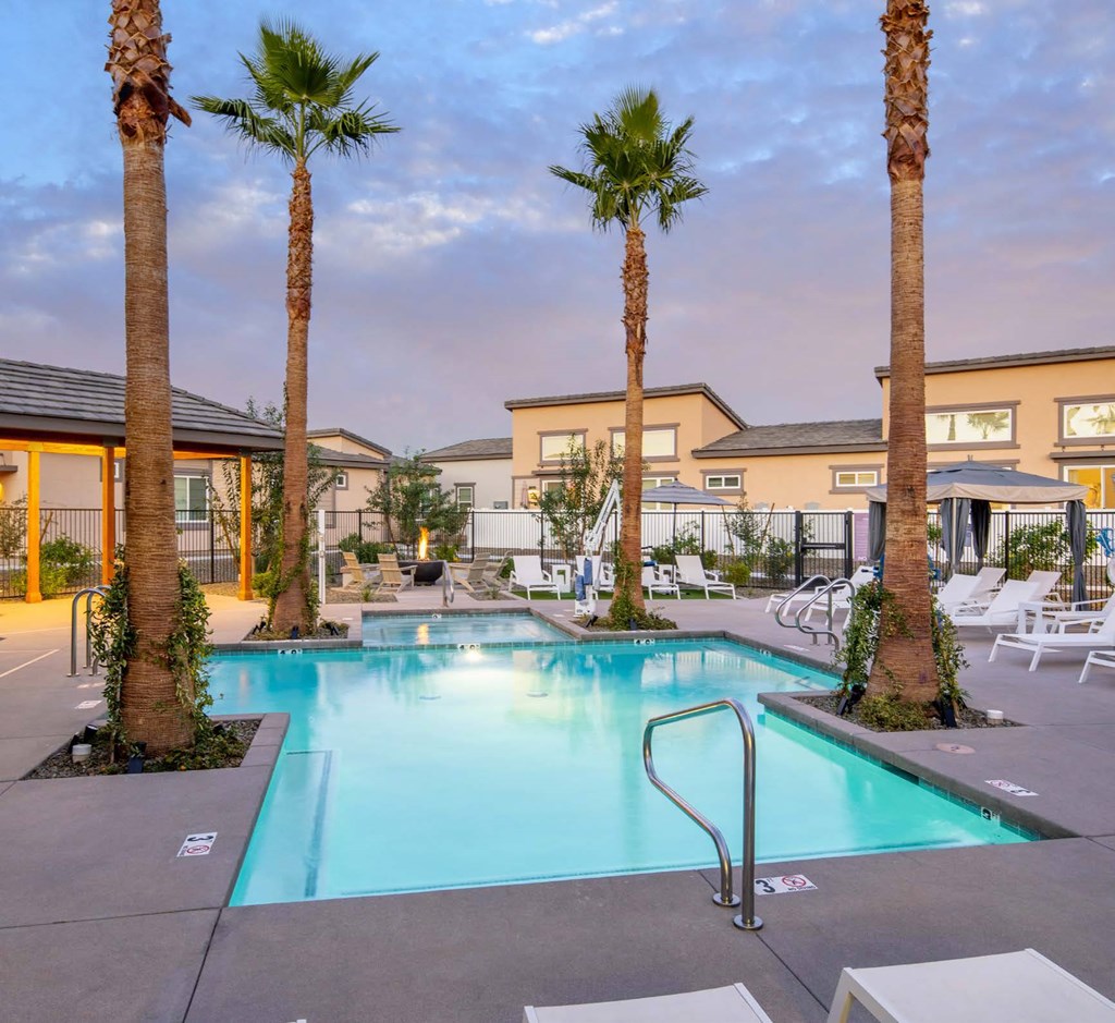 a swimming pool with palm trees and chairs around it a swimming pool with palm trees and chairs around it at Grandstone at Sunrise, Peoria, AZ, 85383